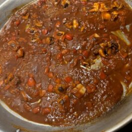 Adding tomato paste, paprika, and saffron to a Spanish paella