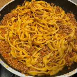 Tagliatelle al Bolognese in the pan combining the sauce with the pasta