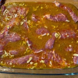 Marinading pork chop meat in a wine and garlic sauce for tender bifana pork chop sandwiches