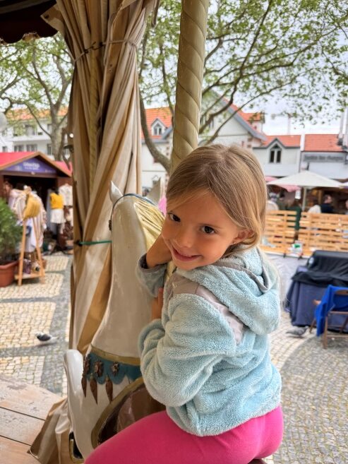 Riding the merry go-round in Jardim Visconde da Luz in central Cascais, Portugal.